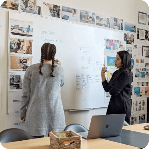 Two people drawing at a whiteboard